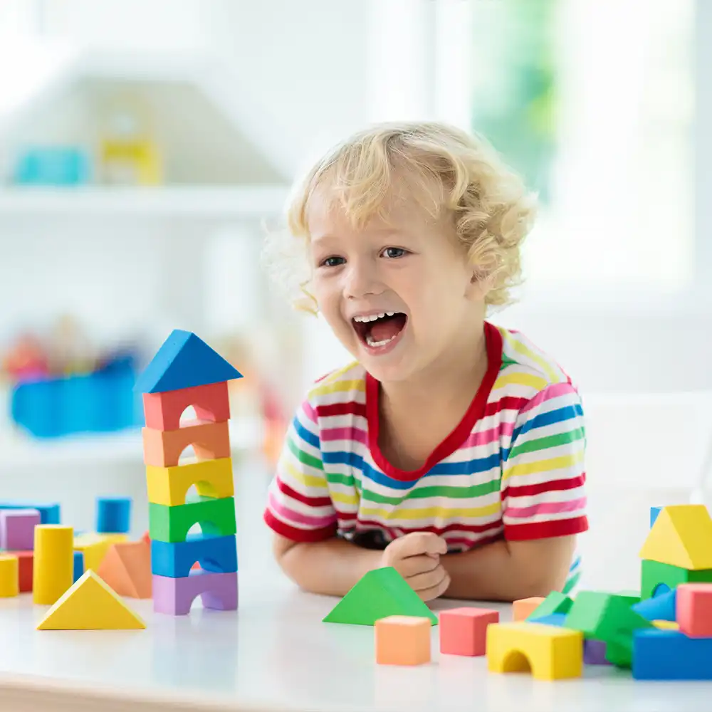Kinderspielzeug. Kind baut einen Turm aus Bauklötzen.
